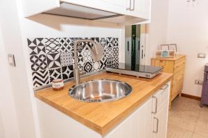 una cucina con lavello in acciaio inossidabile su un bancone di [Centro Storico] Redmood House a 5 min dal mare, Wi-Fi, A/C e Netflix a Barletta