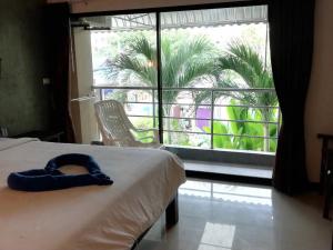 a bedroom with a bed and a window with a palm tree at Smile Home in Patong Beach