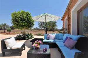 a blue couch and chairs and an umbrella on a patio at Casa Calma in Llucmajor
