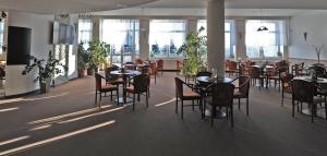 a dining room with tables and chairs and windows at Hotel Churáňov in Stachy