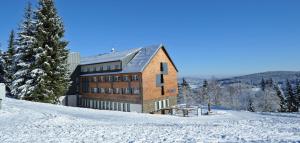 a building on top of a snow covered hill at Hotel Churáňov in Stachy