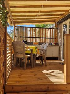 un patio con mesa y sillas en una terraza de madera en Camping La Carabasse Vias-Plage - T4 Neuf, Tout Confort !, en Vias