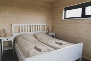 a white bed in a room with two tables and a window at Skógsnes II in Selfoss