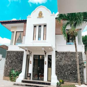 a white house with a palm tree in front of it at Kartiko Palagan Eksklusif Yogyakarta in Kejayan