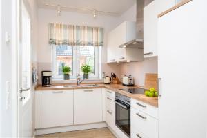 a white kitchen with white cabinets and a window at Alte Waescherei _9464_ in List
