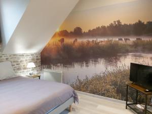 a bedroom with a bed and a tv next to a river at le bonheur des plumes in Montmartin-en-Graignes