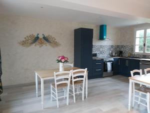 a kitchen with a table and chairs in a room at le bonheur des plumes in Montmartin-en-Graignes