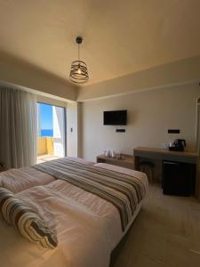 a bedroom with a bed and a desk and a television at Horizon Beach Hotel in Plakias