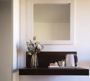 a black shelf with a vase of flowers and a mirror at Villa Azzurra in Lampedusa