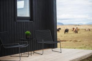 two chairs and a table on a deck with a herd of horses at Skógsnes II in Selfoss