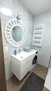 a bathroom with a sink and a mirror and a washing machine at APARTAMENT JARACZA 28/16 in Słupsk