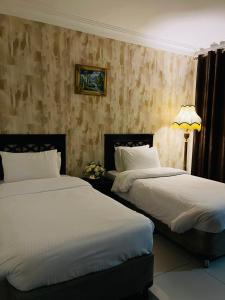 two beds in a hotel room with white sheets at أجنحة أبو قبع الفندقيةAbu Quboh Hotel Suite Apartment in Amman