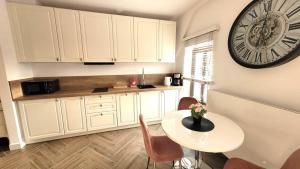 a kitchen with a table and a clock on the wall at APARTAMENT JARACZA 28/16 in Słupsk +11 photos