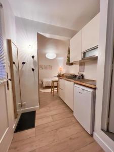 a small kitchen with white cabinets and a table at Escale Cosy à Pontoise Jacuzzi et terrasse in Pontoise