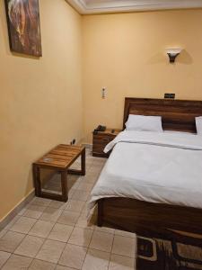 een slaapkamer met een groot bed en een tafel bij Le Baobab in Bamako