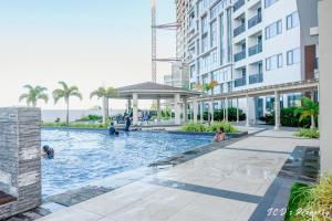 people swimming in a swimming pool in a building at 56sqm. Condo at Mactan Newtown w/Free Beach and Pool Access! in Lapu Lapu City