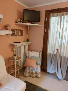 uma sala de estar com uma televisão, uma cadeira e uma janela em Una Franca Camere Di Charme em Biella