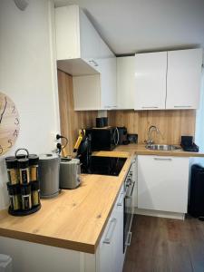 cocina con armarios blancos y encimera de madera en Charmant Duplex proche de Paris, en Saint-Brice-sous-Forêt