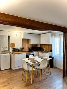 una cocina con mesa blanca y sillas. en Charmant Duplex proche de Paris, en Saint-Brice-sous-Forêt