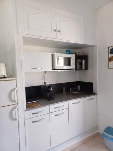 a kitchen with white cabinets and a microwave at Coquet studio indépendant in Els Poblets