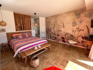 ein Schlafzimmer mit einem Bett und einer Bank in einem Zimmer in der Unterkunft L' Inattendu in Laouque