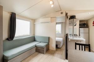 een kleine kamer met een bank, een bed en een keuken bij Ohana Cottage in Fréjus