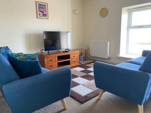 uma sala de estar com duas cadeiras azuis e uma televisão em Shore Enough - Morecambe Sea Front Apartment em Heysham