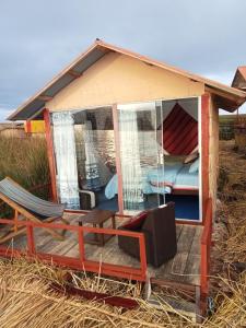 una casa pequeña con porche, cama y silla en Blue Lake House, en Puno