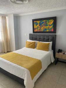 1 dormitorio con 1 cama grande con almohadas amarillas en HOTEL PLAZUELA REAL, en Bucaramanga