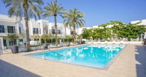 uma piscina com palmeiras e edifícios em Luxury Villa by the sea em Fujairah