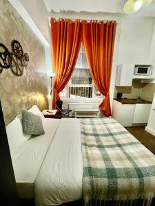 um quarto com uma cama e uma janela com cortinas laranja em Cromwell Apartments em Londres