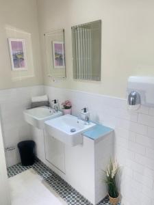 - une salle de bains blanche avec deux lavabos et un miroir dans l'établissement William Wallace Hotel, à Stirling