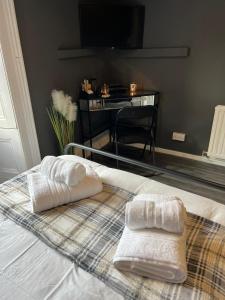 2 toallas en la parte superior de una cama con escritorio en William Wallace Hotel en Stirling