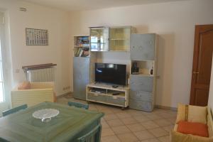 ein Wohnzimmer mit einem TV und einem Tisch in der Unterkunft Villa Gelsomino in Forte dei Marmi
