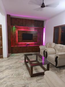 a living room with a couch and a tv at Dhruva Villa in Bidadi