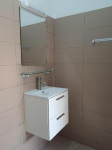 a white bathroom with a sink and a mirror at Appartement Seth in Lomé