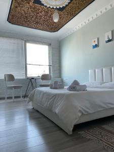 Habitación blanca con cama grande y escritorio. en Agroni Rooms, en Tirana
