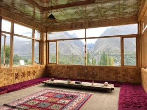 Cette chambre dispose d'une grande fenêtre avec une table et un tapis. dans l'établissement Hunza Verse Luxury Home stay, à Hunza
