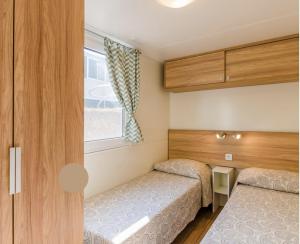 Duas camas num pequeno quarto com uma janela em EUROCAMPINGPACENGO em Pacengo di Lazise