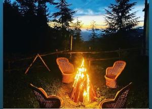a fire pit with four chairs around it at sunset at 4 Bedroom Luxury Bungalow in Manali with Beautiful Scenic Mountain & Orchard View in Manāli