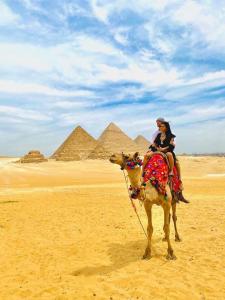 two people riding on a camel in front of pyramids at Pyramids Express Hotel in Cairo