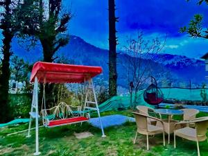 4 Bedroom Luxury Bungalow in Manali with Beautiful Scenic Mountain & Orchard View في مانالي: غرفة بسرير وطاولة