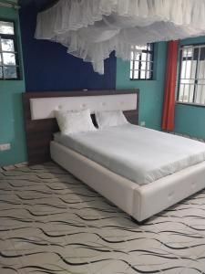 - un grand lit dans une chambre aux murs bleus dans l'établissement Radisson Villa, à Kisumu