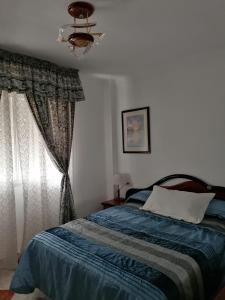 Un dormitorio con una cama con una manta azul y una ventana. en 2 minutes from the beach!!! Great apartment!!!, en Nerja