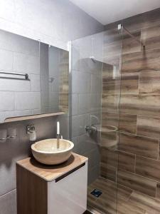 La salle de bains est pourvue d'un lavabo et d'une douche en verre. dans l'établissement Apartmani M.&.B Luks 2, à Mataruška Banja