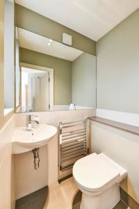 bagno con servizi igienici, lavandino e specchio di Fairway Hosting - No 7 a Londra