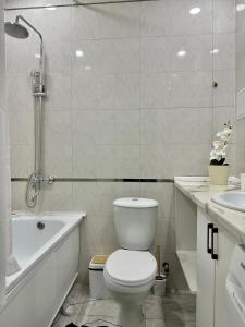 a bathroom with a toilet and a tub and a sink at Студия ОАЗИС с видом на Коктобе in Almaty