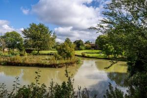 um rio num campo com árvores e nuvens em Lake View em Mellis