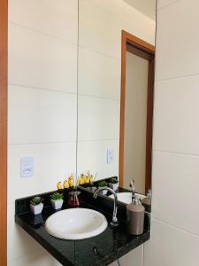 a bathroom with a sink and a mirror at Lindo apto com piscina em Praia Grande - QX01H in Solemar