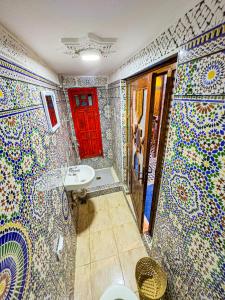 baño con paredes de mosaico y puerta roja en Hostel Speakeasy Fes, en Fez